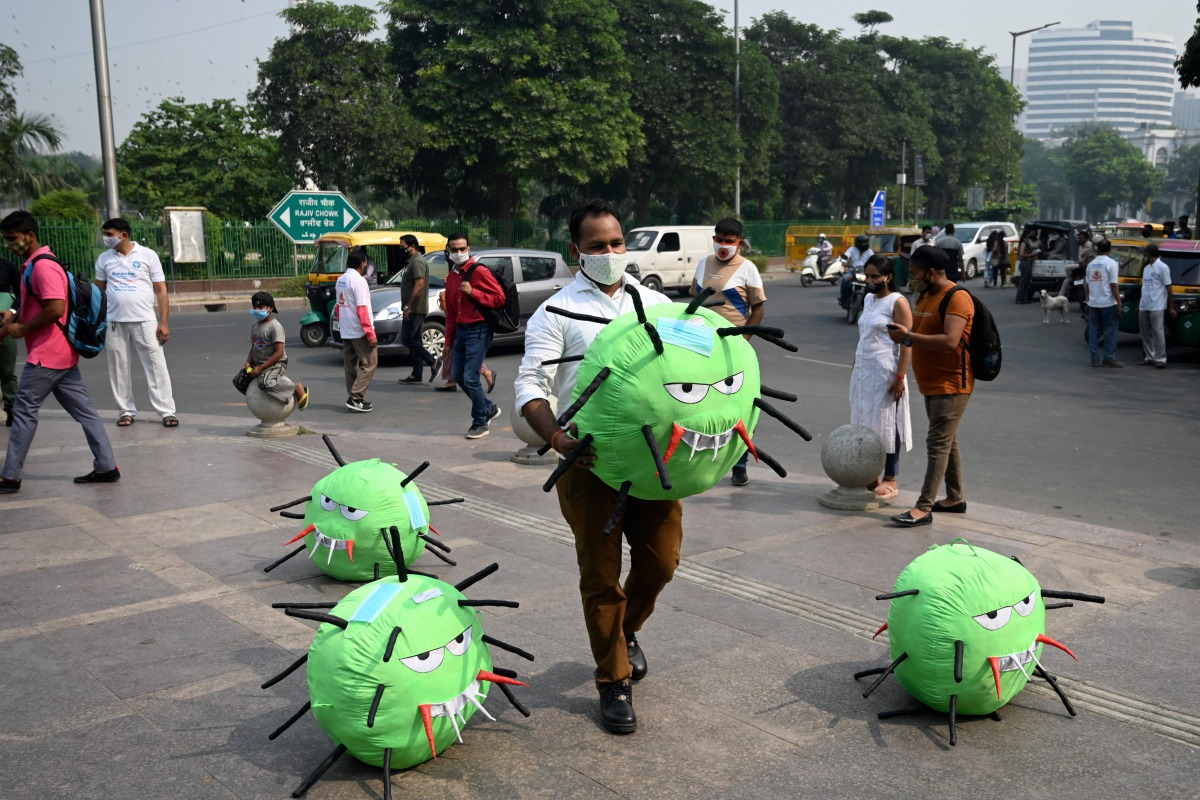 TOPSHOT - An officer from the district magistrate office holds a Covid-19 coronavirus-themed mascot in a market area during an awareness campaign against coronavirus and rising air pollution levels in New Delhi on October 26, 2020. / AFP / Sajjad HUSSAIN