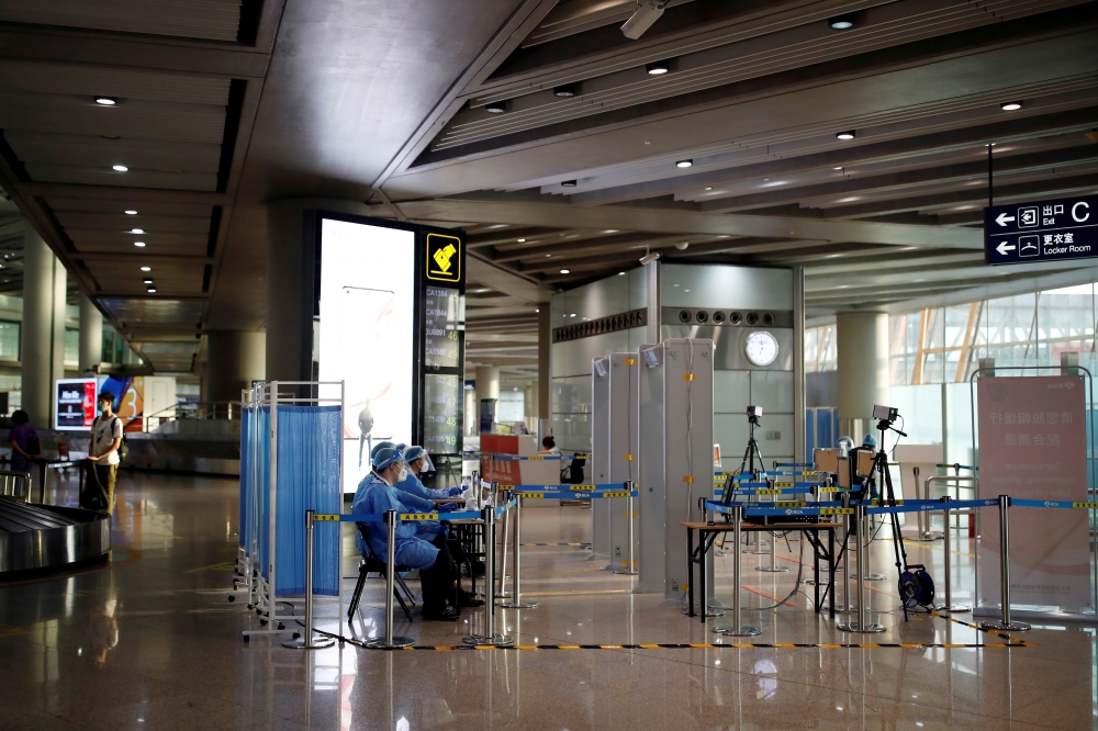 Staff members in protective suits sit at a checkpoint at Beijing Capital International Airport, following new cases of the coronavirus disease (COVID-19) infections, in Beijing, China June 16, 2020. REUTERS/Carlos Garcia Rawlins/File Photo