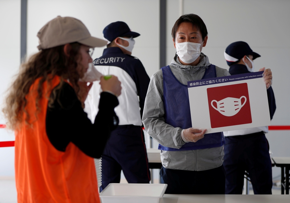 Officials wearing protective masks conduct a test session of screening measures for Tokyo Olympic games spectators, including coronavirus disease (COVID-19) countermeasures at Tokyo Big Sight, Japan October 21, 2020. REUTERS/Issei Kato/File Photo
