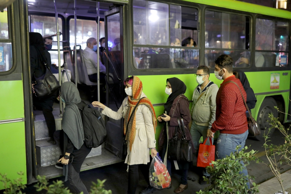 Iranian People wearing protective masks as they board a bus, amid the outbreak of the coronavirus disease (COVID-19), in Tehran, Iran November 11, 2020. Picture taken November 11, 2020. Majid Asgaripour/WANA