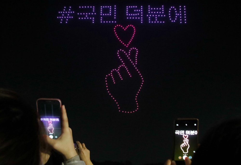 Spectators take photos as 315 illuminated drones perform a routine to display messages and images of support for South Korea amid the COVID-19 coronavirus pandemic, at a park in Seoul on November 13, 2020. - South Korea OUT