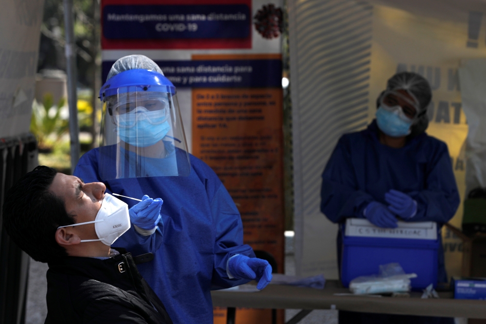 A healthcare worker wearing personal protective equipment (PPE) takes a swab sample from a man to be tested for the coronavirus disease (COVID-19) in Mexico City, Mexico November 13, 2020. Picture taken November 13, 2020. REUTERS/Carlos Jasso