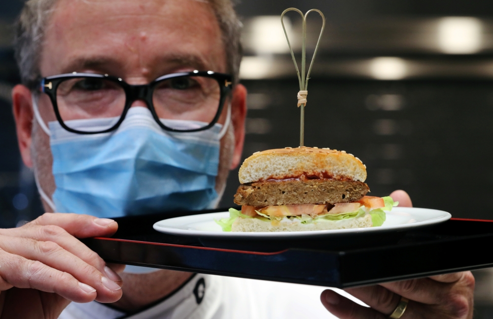 Chef Sam Brunschweiler wears a protective mask as he displays a pea protein-based hamburger with vegan juicy meat flavor, tomato, salad and sesame bun on a plate at flavour maker Givaudan's innovation centre in Kemptthal, Switzerland October 29, 2020. Reu