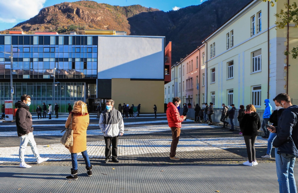 People line up on November 20, 2020 outside a Covid testing facility set up at the Rosenbach Civic Center in the Oltrisarco district of Bolzano, South Tyrol, Northern Italy, waiting to undergo a free rapid antigen nasopharyngeal swab test for COVID-19, wi