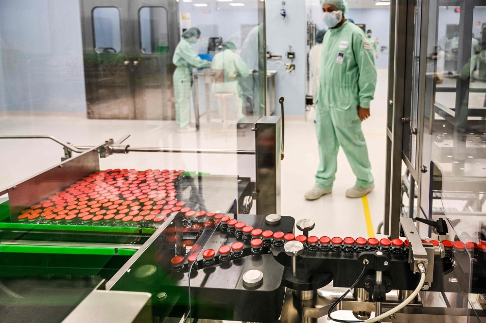 In this file photo taken on September 11, 2020 A laboratory technician supervises capped vials during filling and packaging tests for the large-scale production and supply of the University of Oxford’s COVID-19 vaccine candidate, AZD1222, conducted on a h
