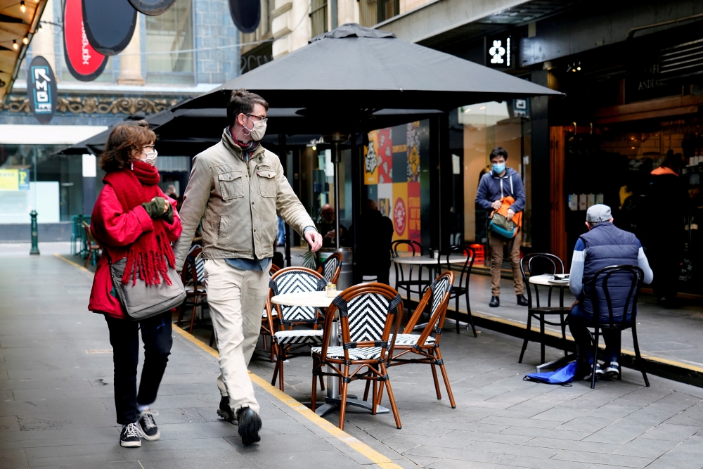 People walk past a cafe after the coronavirus disease (COVID-19) restrictions were eased for the state of Victoria, in Melbourne, Australia, October 28, 2020. REUTERS/Sandra Sanders