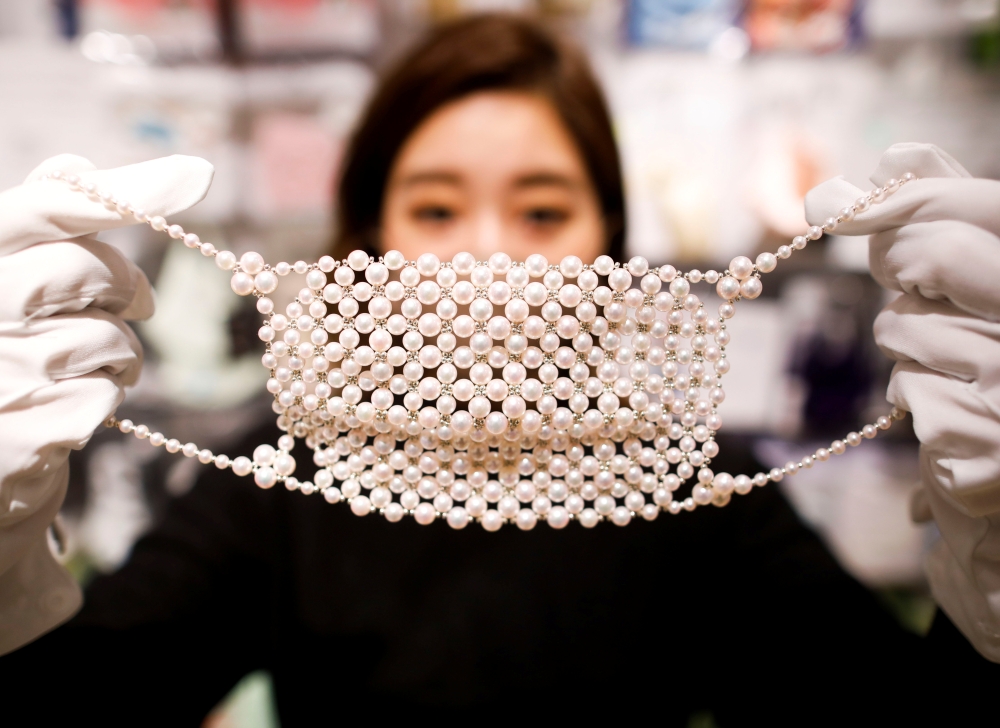 An employee of Cox Co, the operation company of the face-mask speciality shop Mask.com, shows off a luxury face mask made with about 330 pearls which is sellig for one million yen ($9,640), at the shop, amid the coronavirus disease (COVID-19) outbreak, in