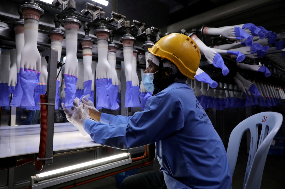 A worker inspects newly-made gloves at Top Glove factory in Shah Alam, Malaysia August 26, 2020. REUTERS/Lim Huey Teng/File Photo