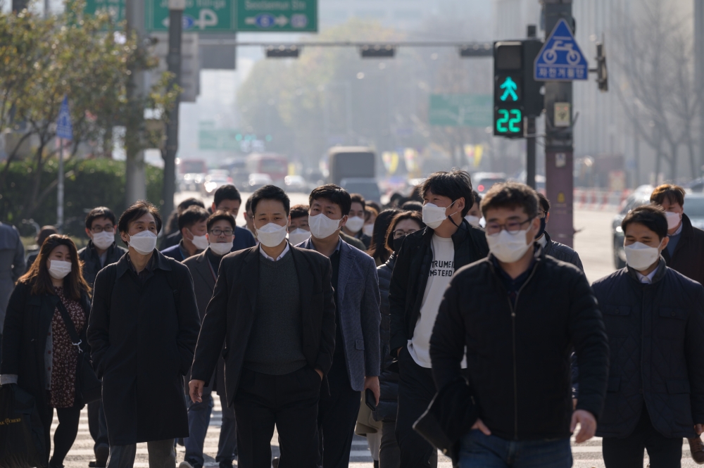 Pedestrians wearing face masks cross a street in Seoul on November 26, 2020. South Korea reported its highest daily number of coronavirus cases since March on November 26, with a surge of new infections sparking fears of a major third wave. / AFP / Ed Jon