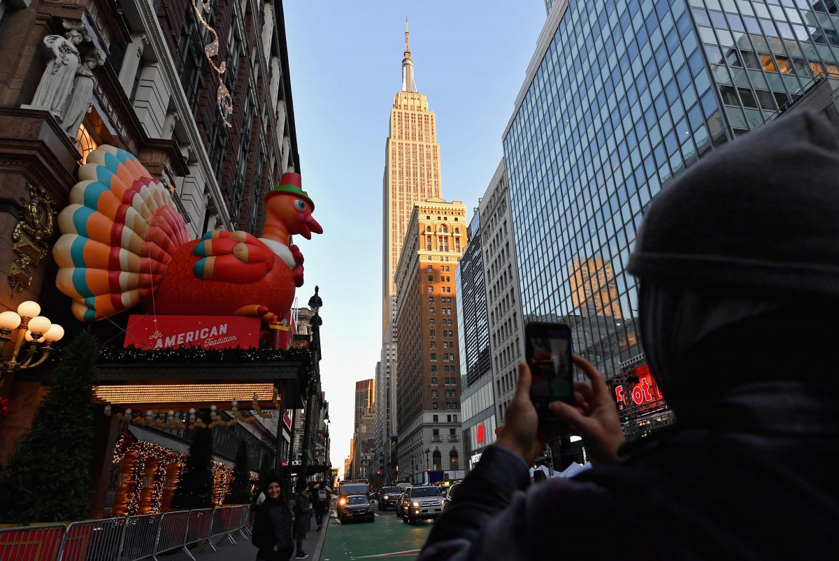 (FILES) In this file photo taken on November 24, 2020, people take photos of Thanksgiving decorations at Macy's Herald Square store in New York City. Thanksgiving is an official American holiday that celebrates one of the country's founding myths. It is f