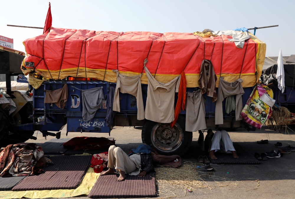 Farmers rest under a truck at a site of a protest against the newly passed farm bills at Singhu border near Delhi, India, November 29, 2020. REUTERS/Anushree Fadnavis