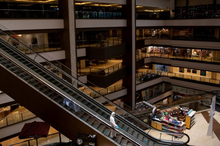 A janitor wearing a hazmat suit to prevent the spread of coronavirus disease (COVID-19), rides an escalator in an almost empty shopping mall in Mandaluyong City, Metro Manila, Philippines, June 3, 2020. REUTERS/Eloisa Lopez/File Photo
