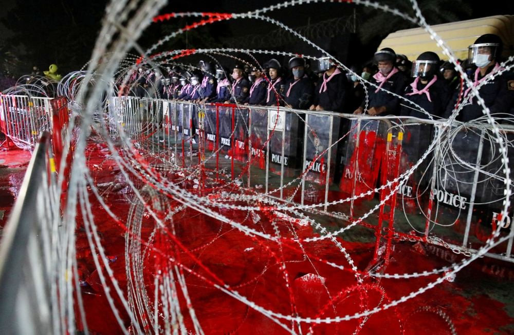 Riot police officers stand guard behind barb wires covered with red paint during a pro-democracy rally demanding Prime Minister Prayuth Chan-ocha to resign and reforms to the monarchy, at 11th Infantry Regiment, in Bangkok, Thailand, November 29, 2020. Re