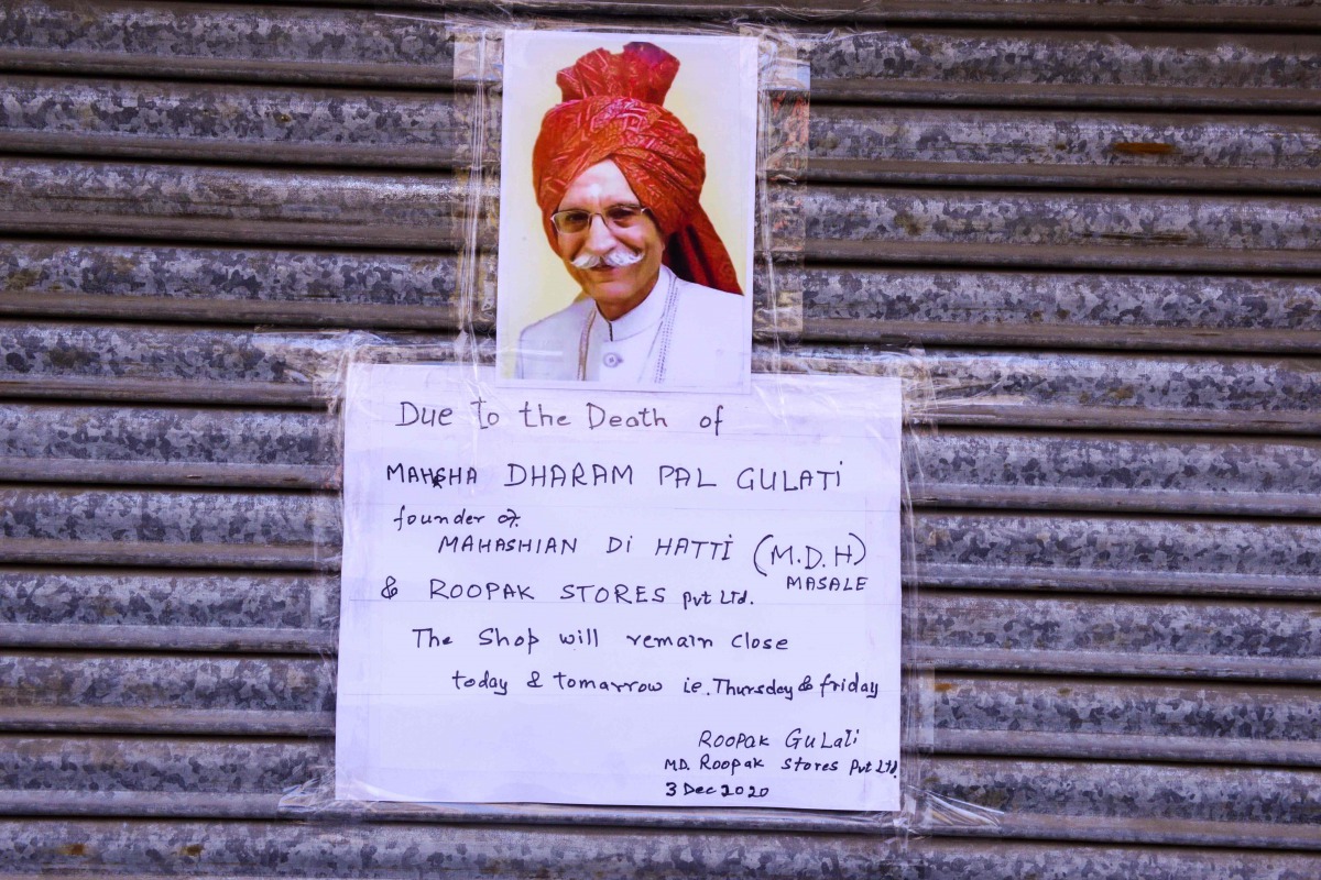 A sign with a picture of Mahashian Di Hatti (MDH) Spices founder Dharampal Gulati is seen at a closed store in New Delhi on December 4, 2020. A former refugee who became India's 