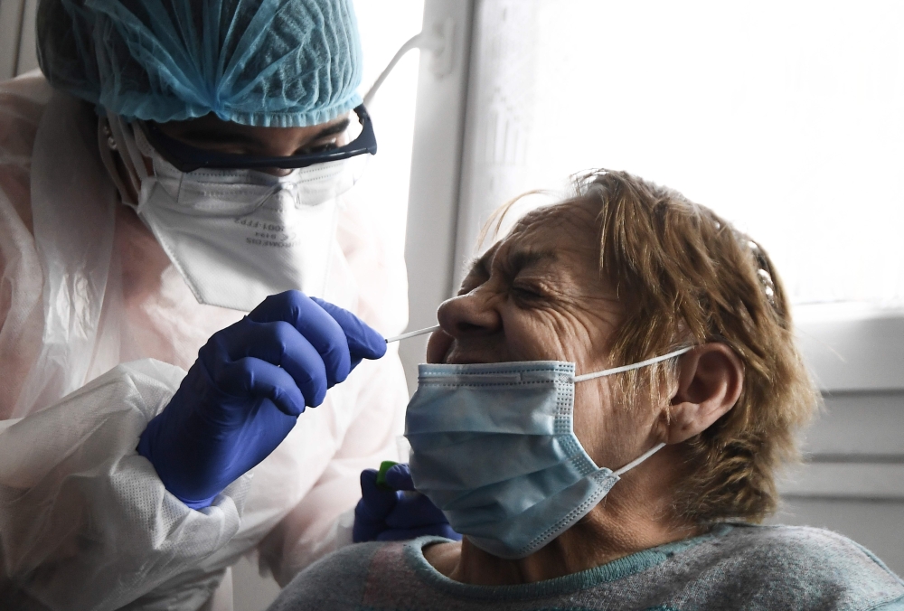(Files) This file photo taken on May 13, 2020, shows a member of the Covisan program testing a member of a family confined at home as they reported a suspected case of Covid-19, in Gennevilliers near Paris. AFP / Alain Jocard 