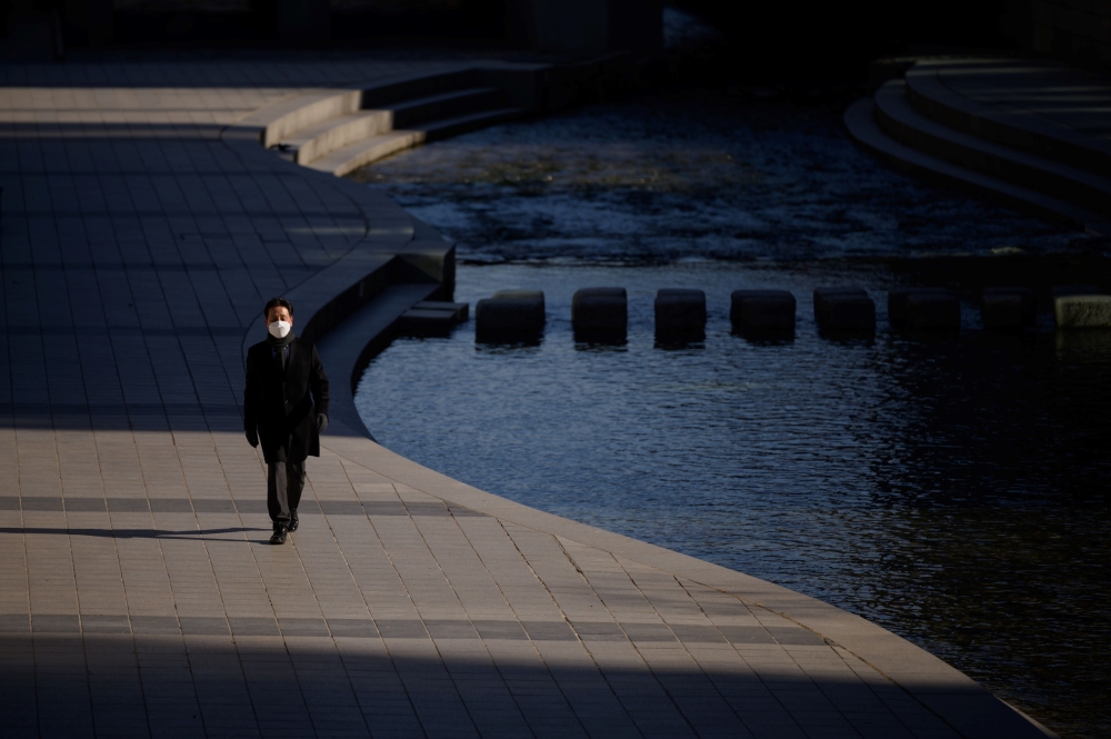 A man wearing a face mask walks alongside the Chongye stream in central Seoul on December 4, 2020. / AFP / Ed JONES