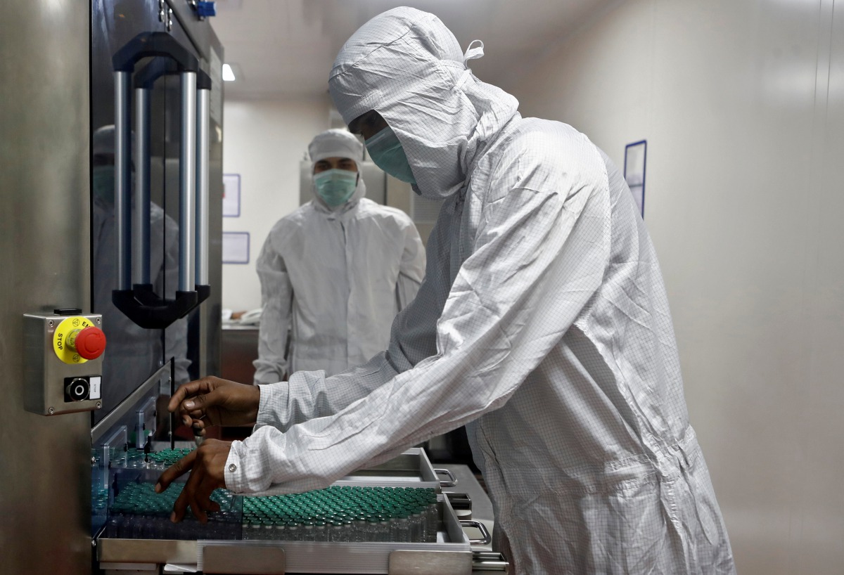 FILE PHOTO: An employee in personal protective equipment (PPE) removes vials of AstraZeneca's COVISHIELD, coronavirus disease (COVID-19) vaccine from a visual inspection machine inside a lab at Serum Institute of India, Pune, India, November 30, 2020. REU