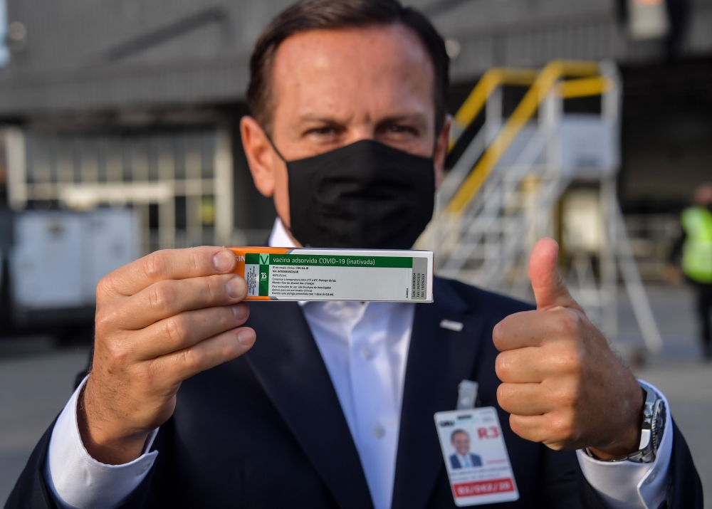 Sao Paulo Governor Joao Doria shows to members of the media a package of the CoronaVac vaccine as containers carrying doses of it are unloaded from a cargo plane that arrived from China at Guarulhos International Airport in Guarulhos, near Sao Paulo, Braz