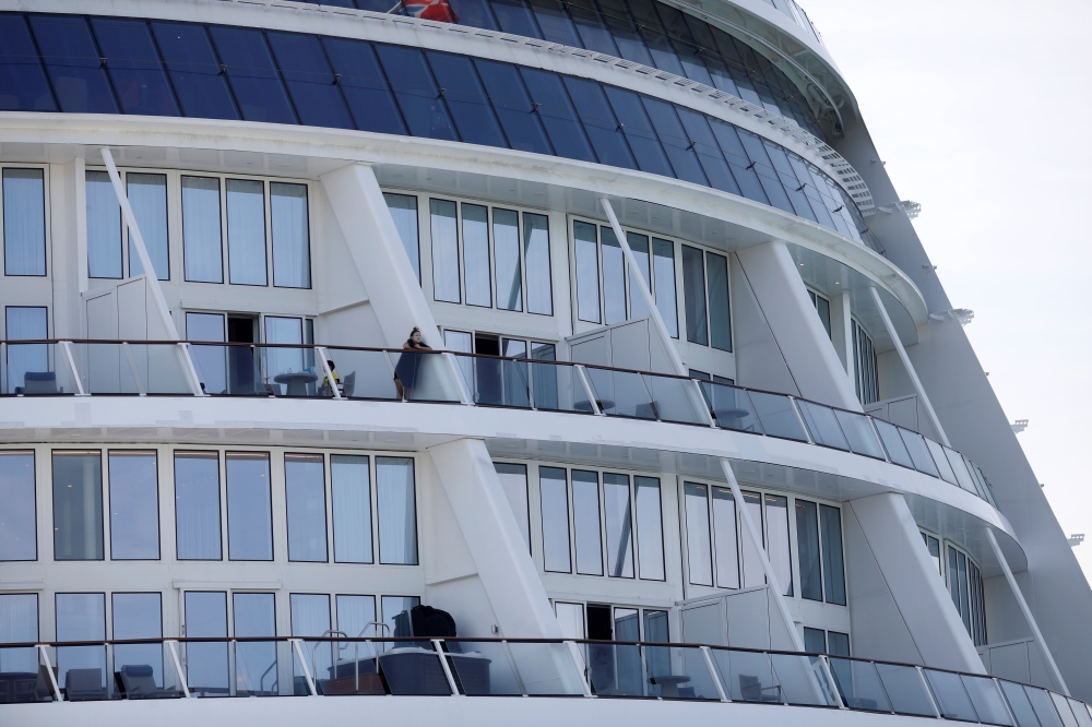 Passengers look from their balconies of the Royal Caribbean's Quantum of the Seas cruise ship, docked at Marina Bay Cruise Center after a passenger tested positive for coronavirus disease (COVID-19) during a cruise to nowhere, in Singapore, December 9, 20
