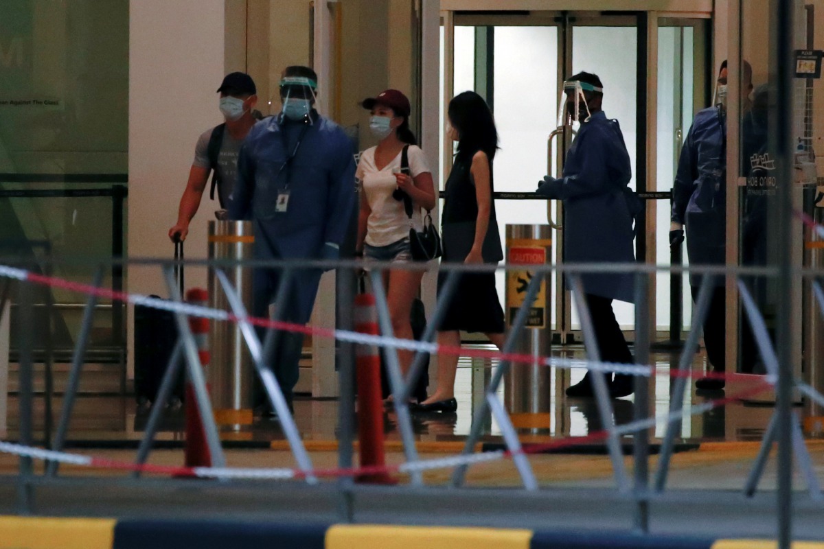 Passengers leave Marina Bay Cruise Center after disembarking from the Royal Caribbean's Quantum of the Seas cruise ship, which is moored after a passenger tested positive for coronavirus disease (COVID-19) during a cruise to nowhere, in Singapore, Decembe