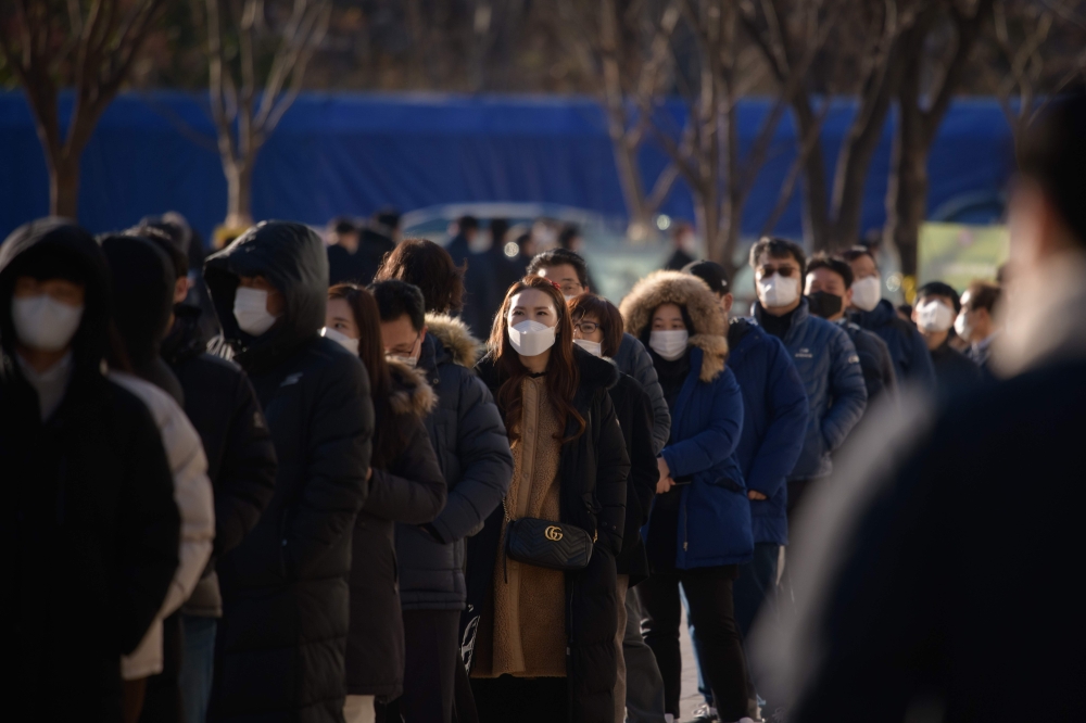 Office workers and city government employees queue at a temporary covid-19 novel coronavirus testing centre outside city hall in Seoul on December 17, 2020. / AFP / Ed JONES