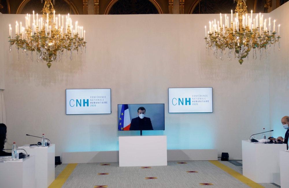 French President Emmanuel Macron, tested positive for the coronavirus disease (COVID-19), is seen on a screen as he attends by video conference a round table for the National Humanitarian Conference (NHC) at the Foreign Ministry in Paris on December 17, 2