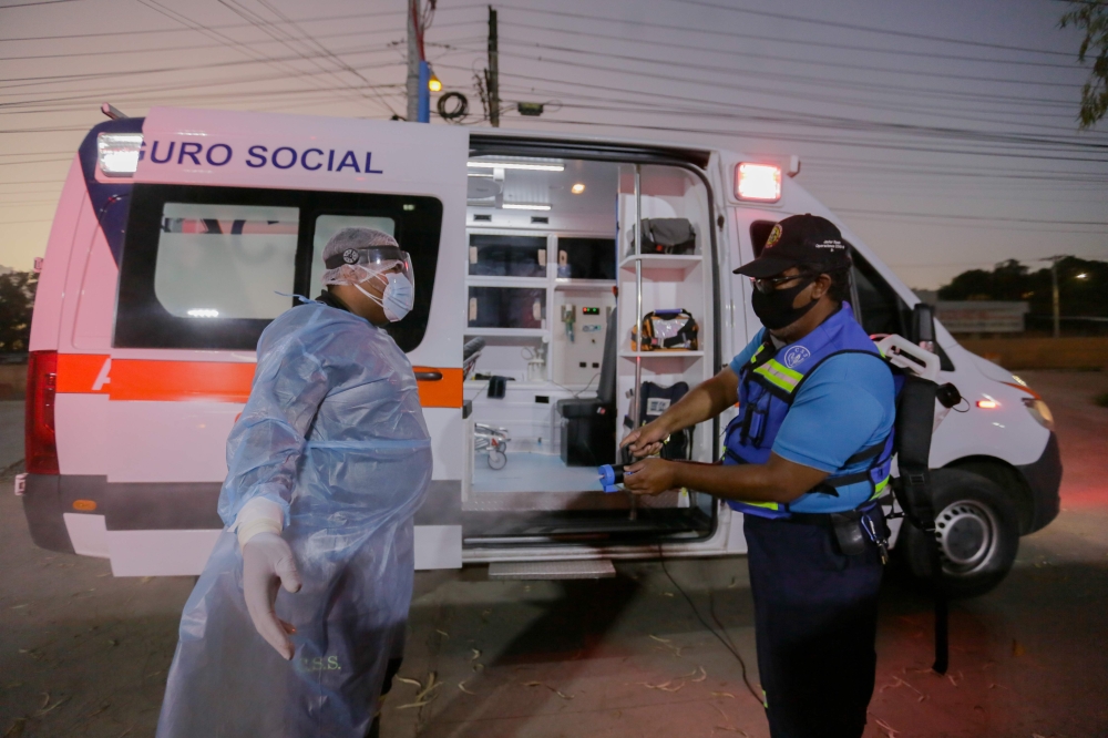 A paramedic is disinfected after transferring a patient infected with Covid-19 in Panama City on December 14, 2020. AFP / STR