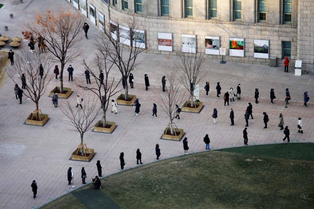 People wait in a line to undergo the coronavirus disease (COVID-19) test at a testing site which is temporarily set up at City Hall Plaza in Seoul, South Korea December 18, 2020. REUTERS/Heo Ran