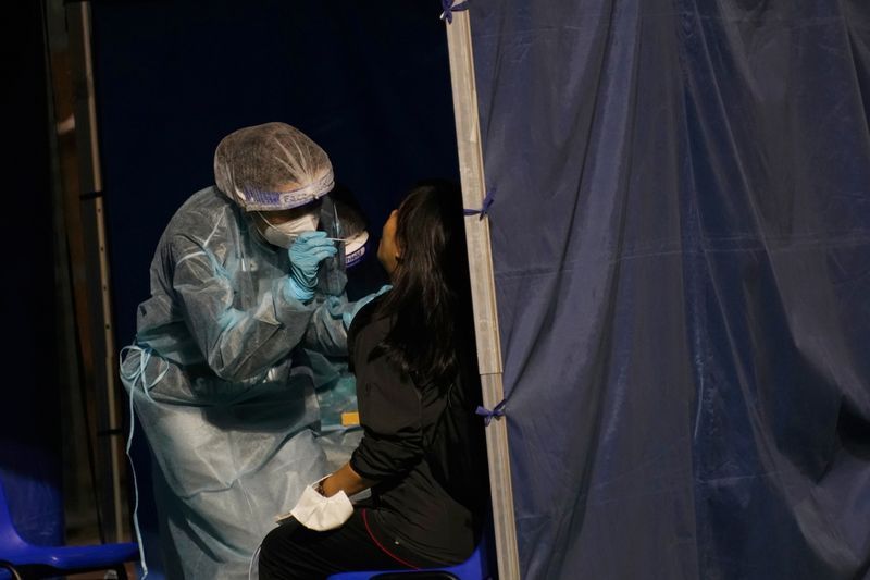 A health worker collects a swab sample from a woman at a makeshift testing centre on a soccer field following the coronavirus disease (COVID-19) outbreak in Hong Kong, China December 8, 2020. REUTERS/Lam Yik