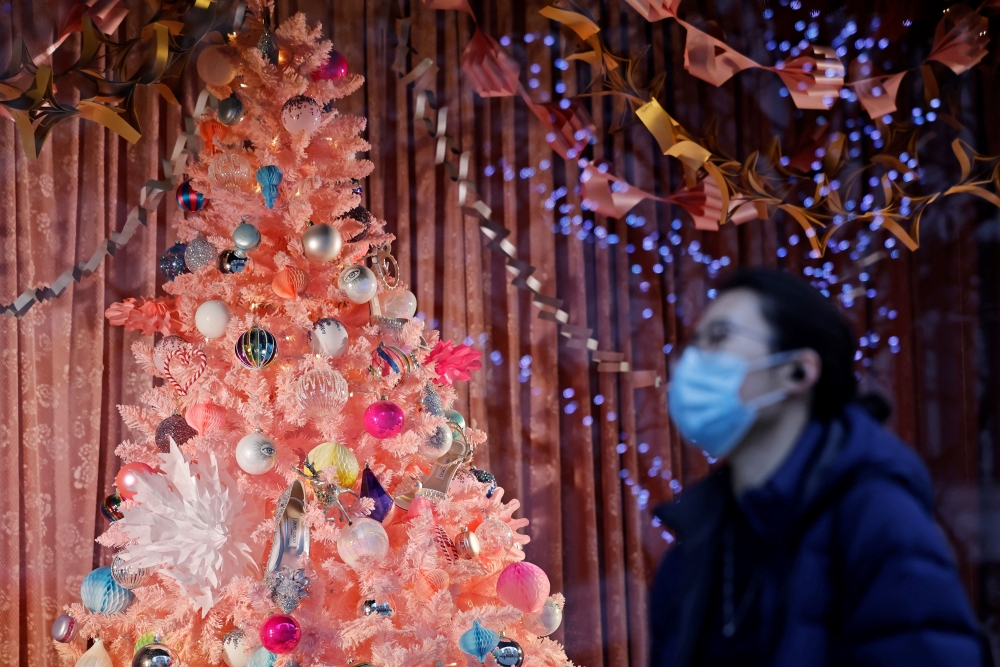  A pedestrian wearing a face mask or covering due to the COVID-19 pandemic, walks past a Christmas-themed display in a shop window on Oxford Street in central London on December 22, 2020.  AFP / Tolga Akmen
