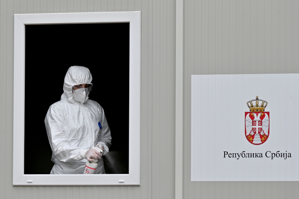 A medical worker disinfects the window of a testing booth while waiting for patients to test for coronavirus at the Institute of Virology, Vaccines and Sera “Torlak” in Belgrade on December 24, 2020. 