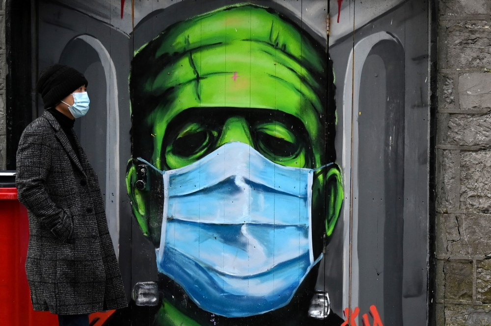 A man walks past a graffiti of a Frankenstein wearing a protective face mask on a doorway amid the spread of the coronavirus disease (COVID-19) pandemic, in Galway, Ireland, December 22, 2020. REUTERS/Clodagh Kilcoyne