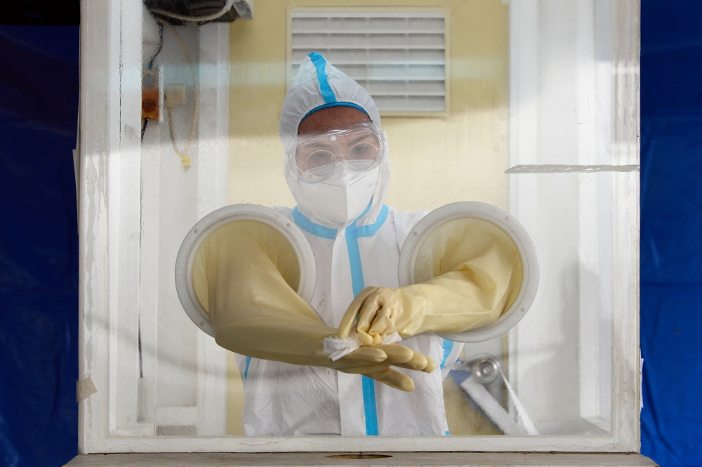 A health worker wearing a protective suit amid the coronavirus disease (COVID-19) pandemic disinfects her hands at a testing station, in Makati City, Metro Manila, Philippines, December 21, 2020. REUTERS/Lisa Marie David