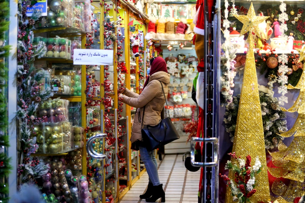An Iranian woman, wearing a protective face mask, shops at a store selling Christmas decorations in the capital Tehran on December 22, 2020. / AFP / ATTA KENARE