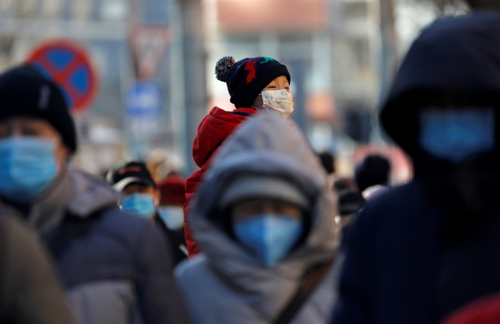 People wearing masks walk in a street in Beijing?s central business district (CBD) during morning rush hour, following the coronavirus disease (COVID-19) outbreak, in China December 8, 2020. REUTERS/Tingshu Wang/File Photo