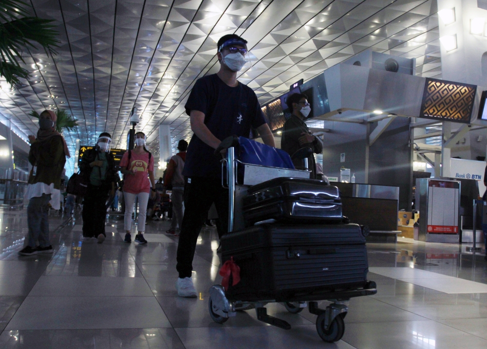 Passengers wearing protective face masks walk at the Soekarno-Hatta Airport amid the coronavirus disease (COVID-19) pandemic, in Tangerang, on the outskirts of Jakarta, Indonesia December 23, 2020. Antara Foto/Muhammad Iqbal/via Reuters. 
