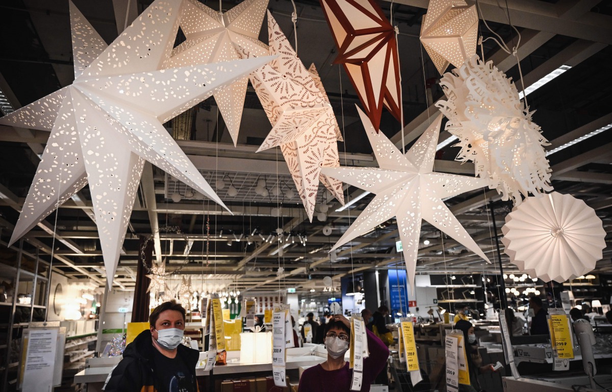 People wearing face masks look at the Christmas decorations while shopping in Moscow on December 28, 2020, amidst the Covid-19 pandemic caused by the novel coronavirus. Russia confirmed 27,787 new daily Covid-19 cases including 6,253 in Moscow. / AFP / Al
