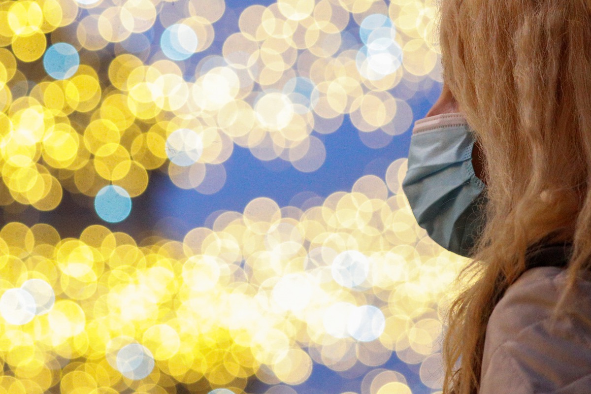 A person wearing a protective mask looks on in front of Christmas lights one day before Italy goes back to a complete lockdown over the Christmas period as part of efforts put in place to curb the spread of the coronavirus disease (COVID-19), in Rome, Ita