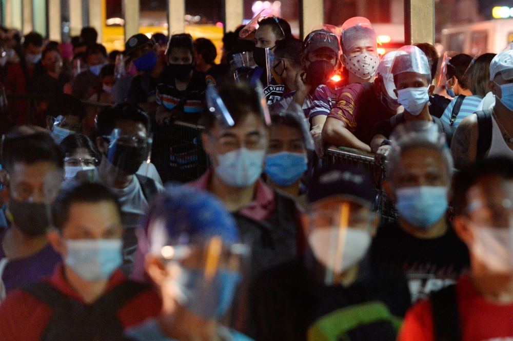People wearing face masks and face shields as protection against the coronavirus disease (COVID-19) queue at a bus stop, in Quezon City, Metro Manila, Philippines, December 23, 2020. REUTERS/Lisa Marie David