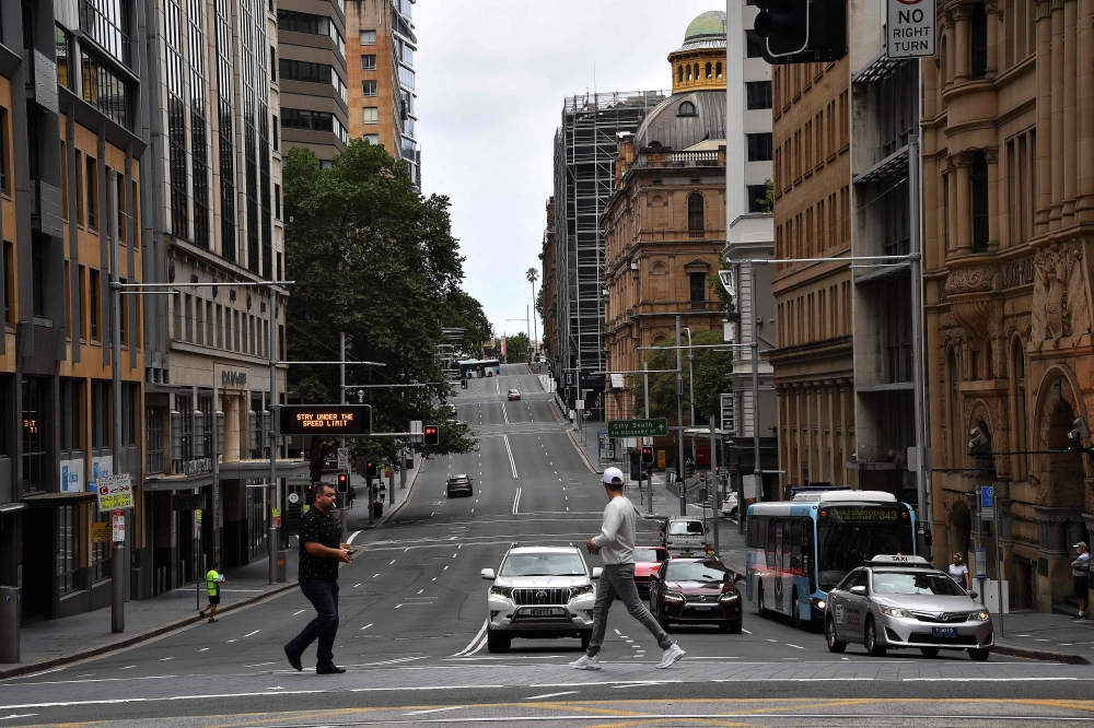 Pedestrian crosses a road usually packed with heavy traffic in the central business district in Sydney on December 30, 2020, as authorities work to suppress a growing cluster of Covid-19 coronavirus cases in Australia's most populous city. / AFP / Saeed K