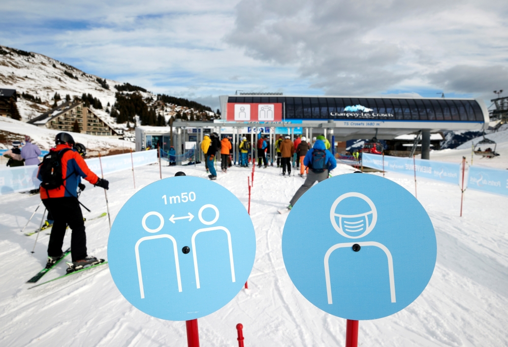 Skiers pass the restriction signs to line up at the chairlift at Les Portes du Soleil ski resort during the global outbreak of the coronavirus disease (COVID-19), in Les Crosets, Switzerland, December 19, 2020. REUTERS/Denis Balibouse/File Photo