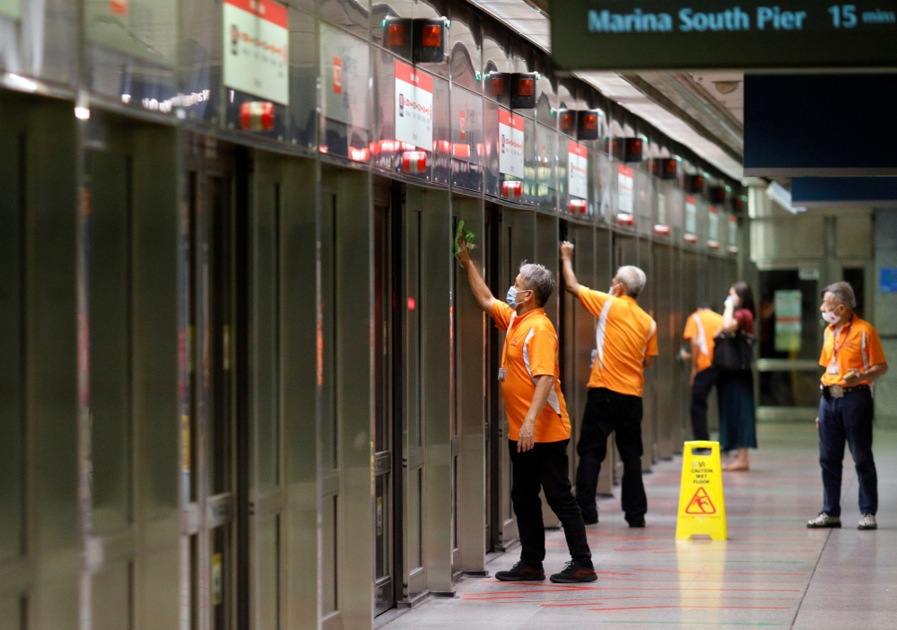 Workers wipe down doors at a train station during the coronavirus disease (COVID-19) outbreak in Singapore August 17, 2020. REUTERS/Edgar Su/File Photo