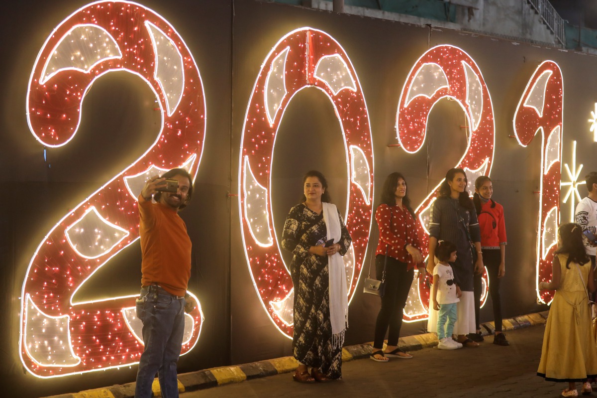 People pose for a picture next to an installation at a mall on New Year's Eve, amid the spread of the coronavirus disease (COVID-19) in Mumbai, India, December 31, 2020. REUTERS/Francis Mascarenhas
