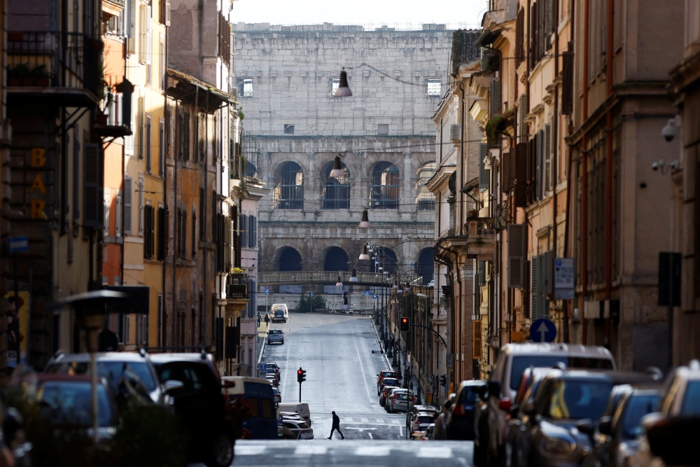 A man crosses a street near the Colosseum on New Year's Day amid the coronavirus disease (COVID-19) outbreak in Rome, Italy January 1, 2021. REUTERS/Guglielmo Mangiapane