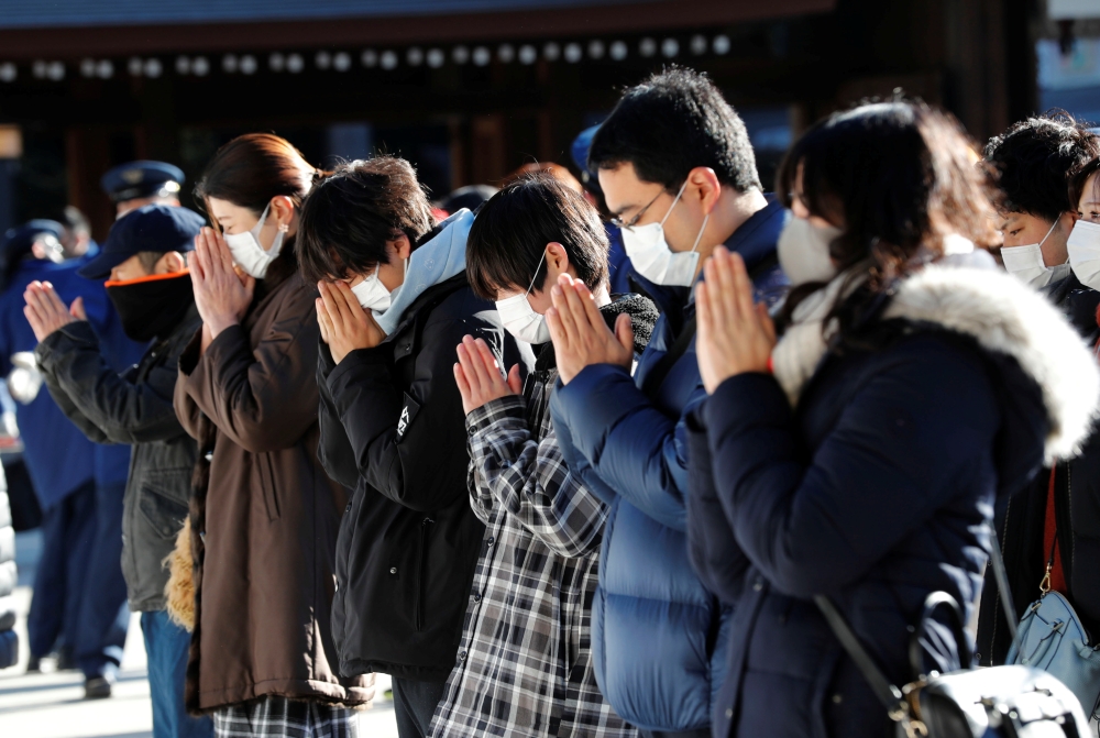 People wearing protective masks amid the coronavirus disease (COVID-19) outbreak, pray on the first day of the new year at the Meiji Shrine in Tokyo, Japan, January 1, 2021. Reuters/Kim Kyung-Hoon