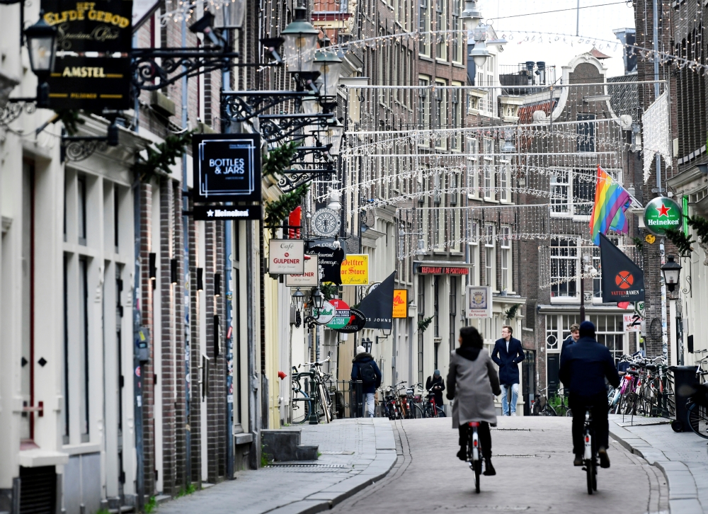 FILE PHOTO: People ride bikes on an empty street as Netherlands has gone into lockdown as the spread of the coronavirus disease (COVID-19) continues in Amsterdam, Netherlands December 15 2020, REUTERS/Piroschka van de Wouw