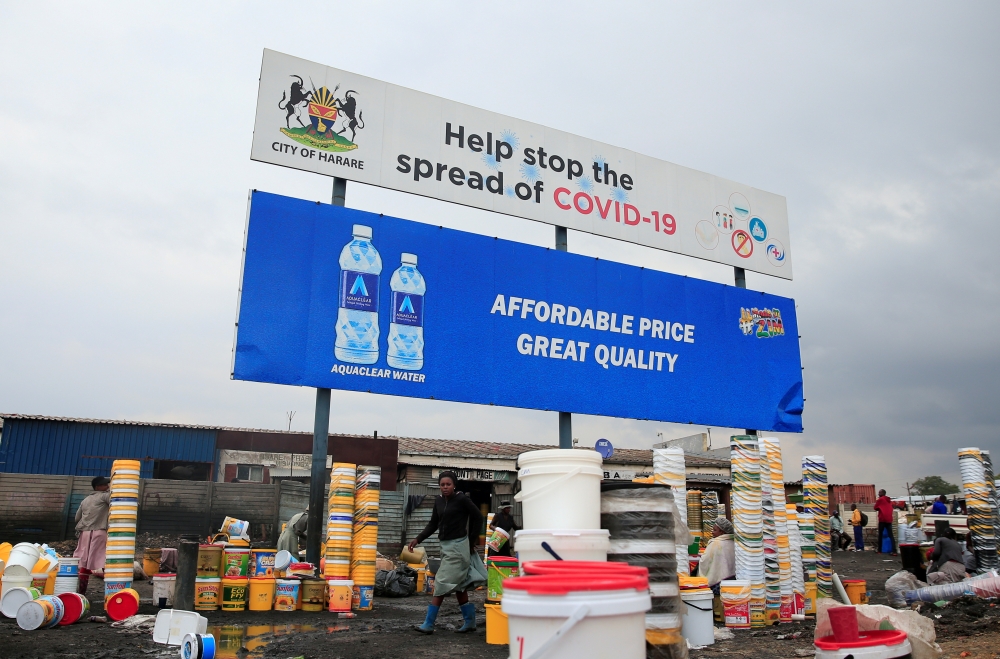 FILE PHOTO: Containers and other goods are sold beneath a coronavirus disease (COVID-19) awareness billboard at a marketplace in Harare, Zimbabwe, November 26, 2020. REUTERS/Philimon Bulawayo