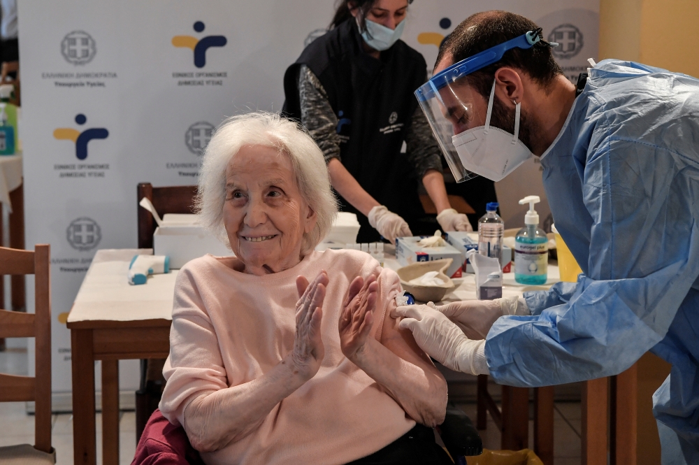 An elderly woman claps her hands after receiving a vaccine against the coronavirus disease (COVID-19) at a nursing home in Athens, Greece, January 4, 2021. Louisa Gouliamaki/Pool via REUTERS
