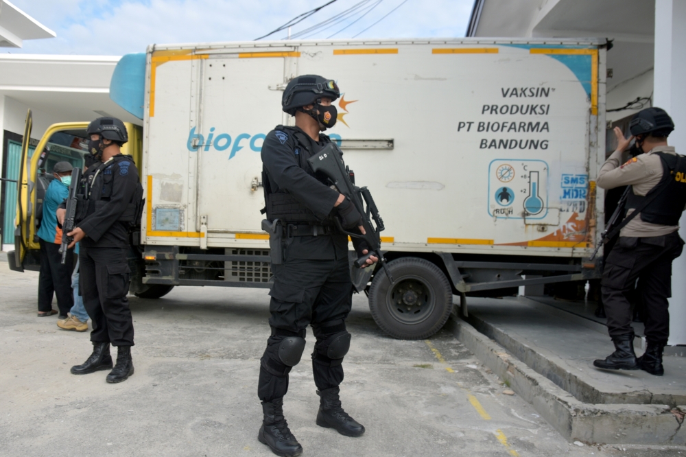 Armed police officers stand guard next to a truck containing Sinovac's vaccine for coronavirus disease (COVID-19) during its distribution in Pekanbaru, Riau province, Indonesia, January 5, 2021 in this photo taken by Antara Foto. Antara Foto/FB Anggoro vi