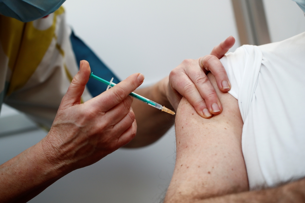 A healthcare worker receives a dose of the Pfizer-BioNTech COVID-19 vaccine at a coronavirus disease vaccination center inside a gymnasium in Taverny near Paris, France, January 9, 2021. REUTERS/Benoit Tessier